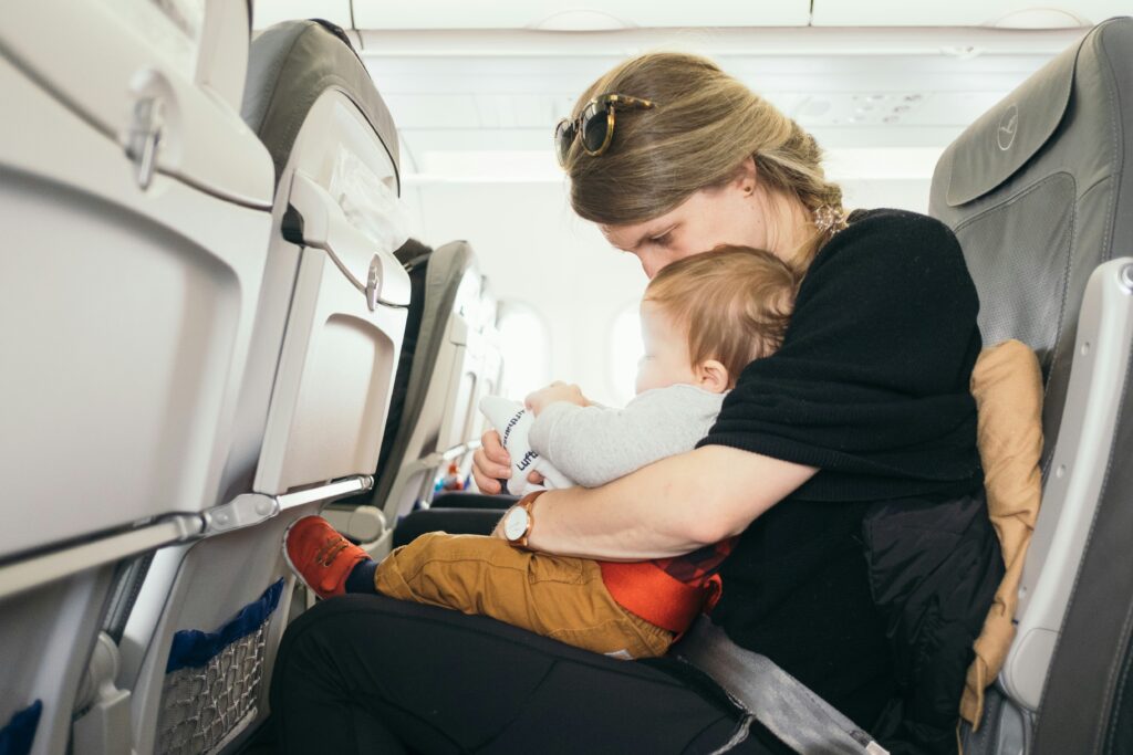 A mama in a plane holding her baby close to her. one tips that makes traveling wit kids easy 