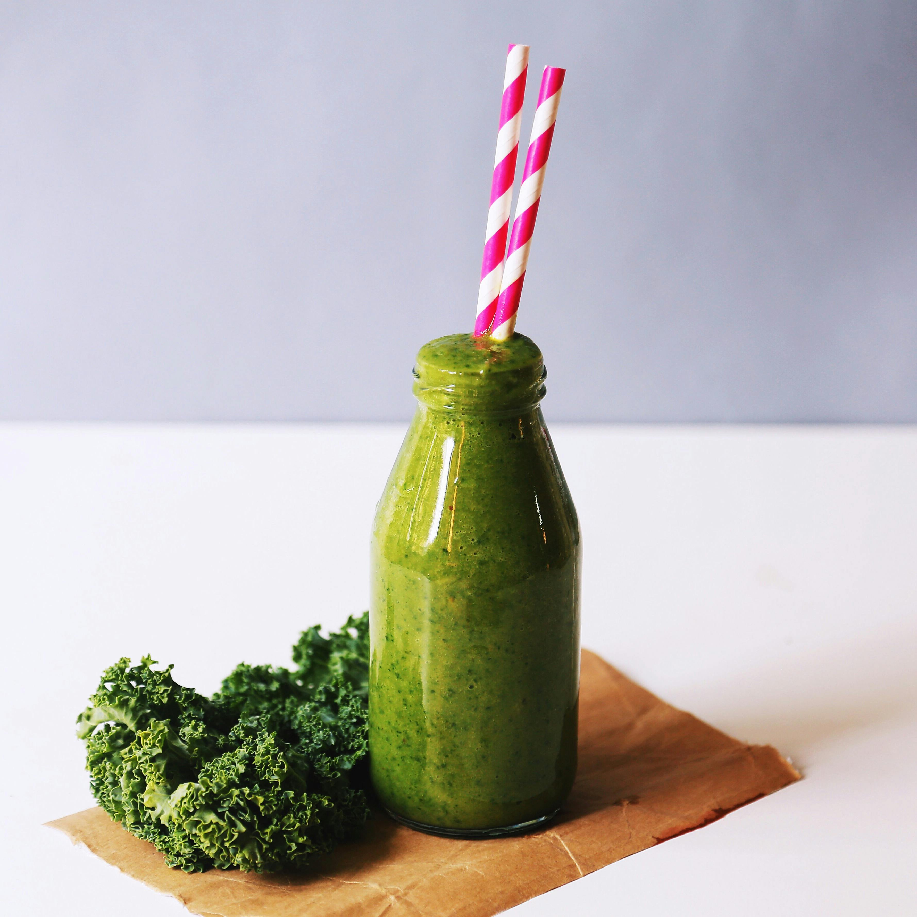 A kale juice for detox in a transparent bottle and on a white table