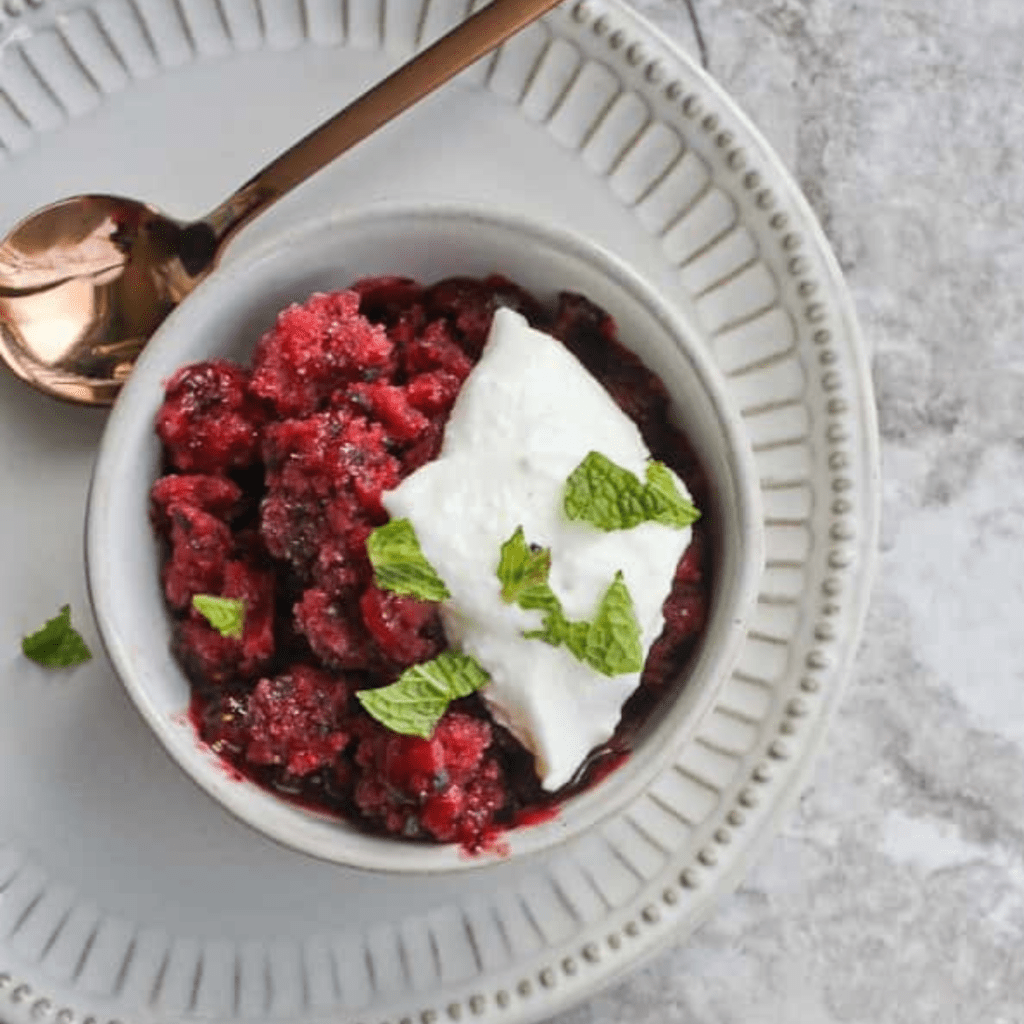 A bowl of berry granita with whipped ricotta. A refreshing summer dessert option for families to enjoy.
