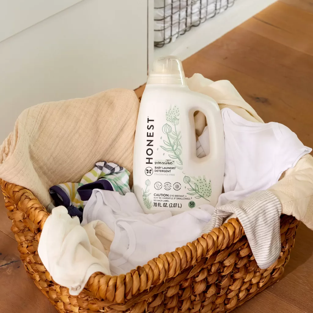 A bottle of the honest comapny non toxic natural laundry in a basket of dirty clothes