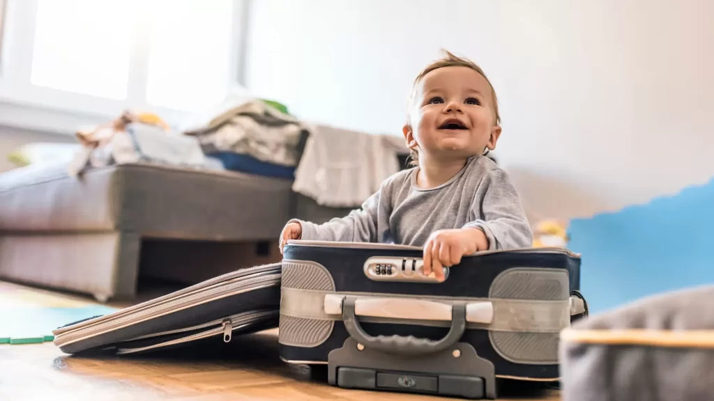 toddler carry-on essentials. A smiling baby inside a suitcase